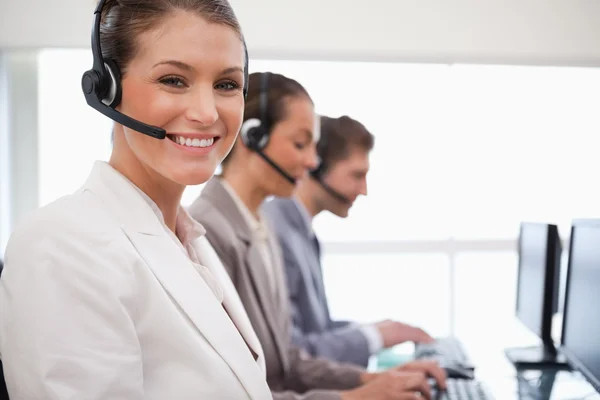 Smiling call center agent colleagues behind her — Stock Photo, Image