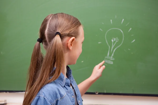 Schoolgirl pointing at a bulb — Stock Photo, Image