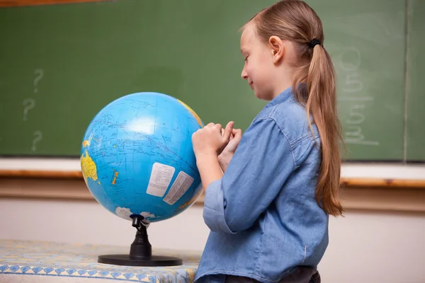 Школьница смотрит на земной шар — стоковое фото