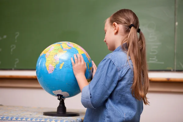 Сосредоточенная школьница смотрит на глобус — стоковое фото