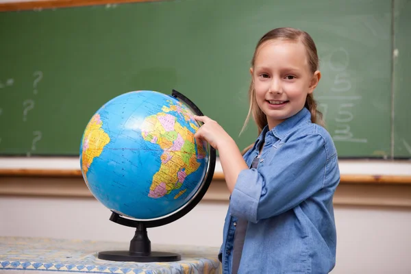 Улыбающаяся школьница смотрит на глобус — стоковое фото