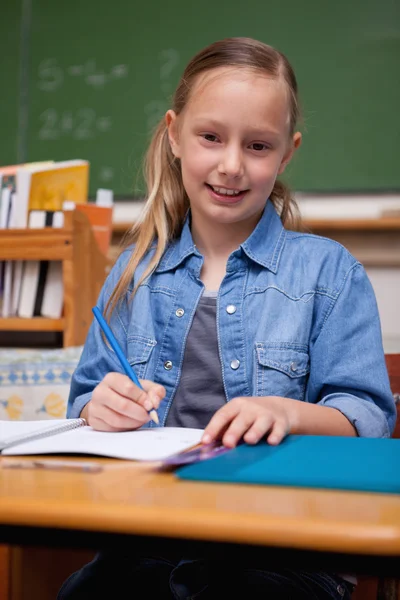Portrait d'une écolière souriante écrivant — Photo