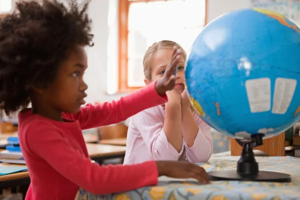 Gelukkig schoolmeisjes kijken naar een globe — Stockfoto
