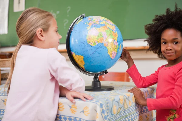 Schattig schoolmeisjes kijken naar een globe — Stockfoto