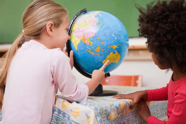 Weinig schoolmeisjes kijken naar een globe — Stockfoto