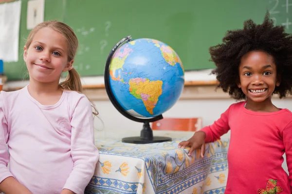 Schoolmeisjes poseren met een globe — Stockfoto