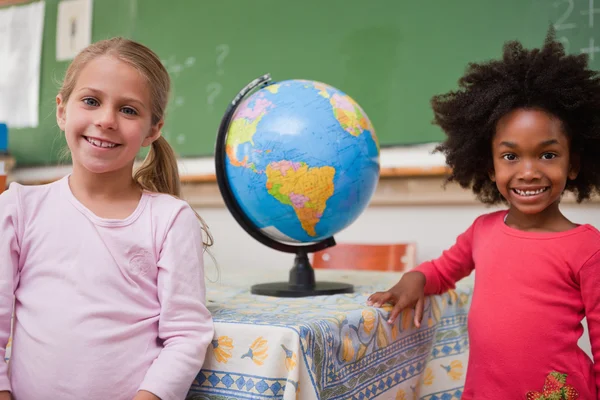 Cute schoolgirls posing with a globe — Stock Photo, Image