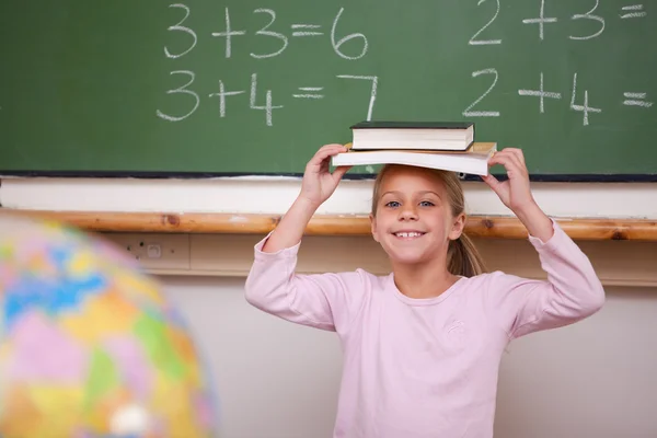 Carino studentessa holding suo libro su suo testa — Foto Stock