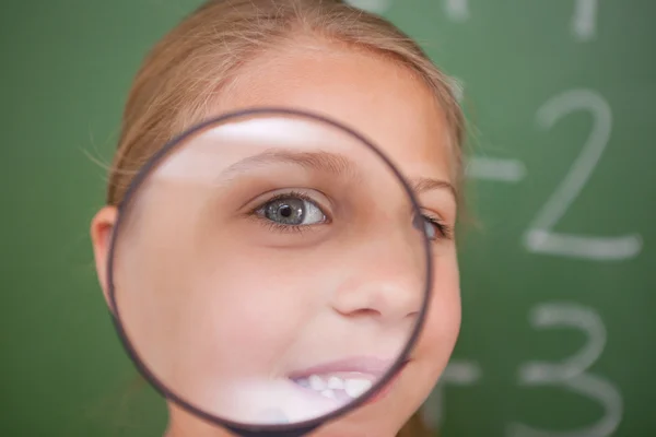 Close up de uma estudante olhando através de uma lupa — Fotografia de Stock