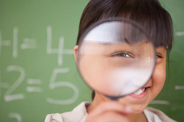 Detailní záběr roztomilá školačka při pohledu skrz zvětšovací sklo — Stock fotografie