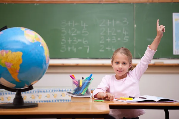 Schattig schoolmeisje verhogen haar hand om een vraag te beantwoorden — Stockfoto