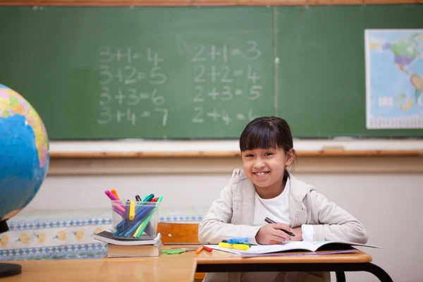 Lachende schoolmeisje puttend uit een kleurboek — Stockfoto