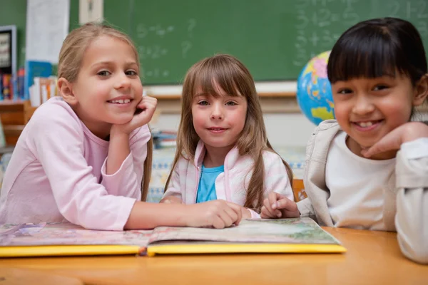 Gelukkig schoolmeisjes een sprookje lezen om hun klasgenoot — Stockfoto