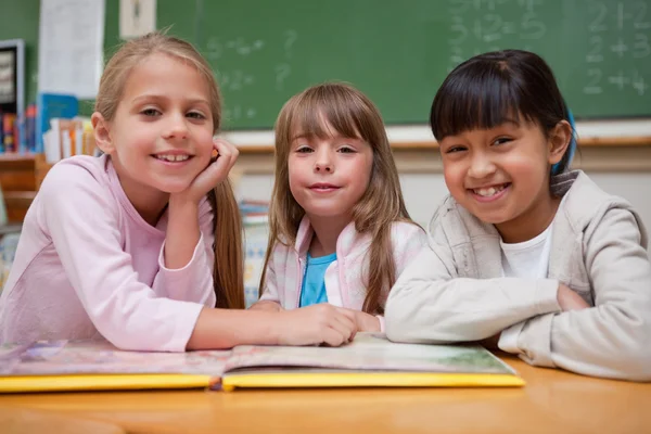 Schoolmeisjes een sprookje lezen om hun klasgenoot glimlachen — Stockfoto