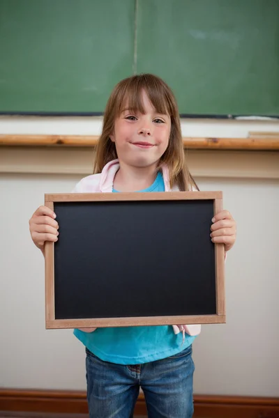 Retrato de uma menina sorridente segurando uma ardósia escolar — Fotografia de Stock