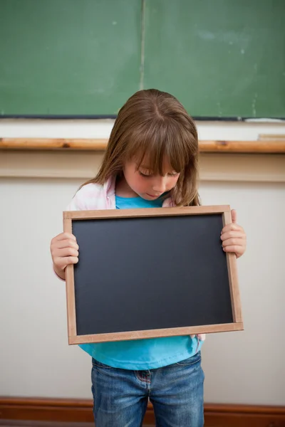 Retrato de uma menina olhando para uma ardósia escola — Fotografia de Stock