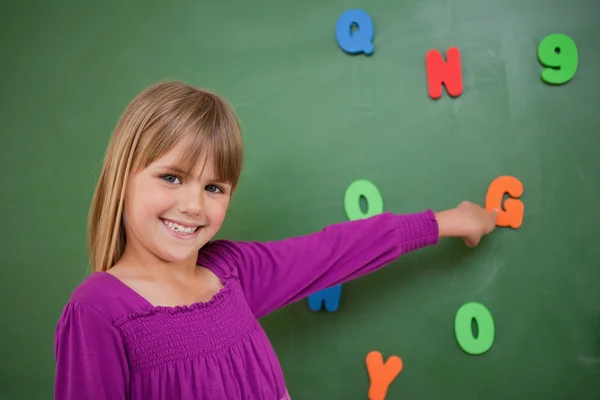 Kleines Schulmädchen zeigt auf einen Brief — Stockfoto