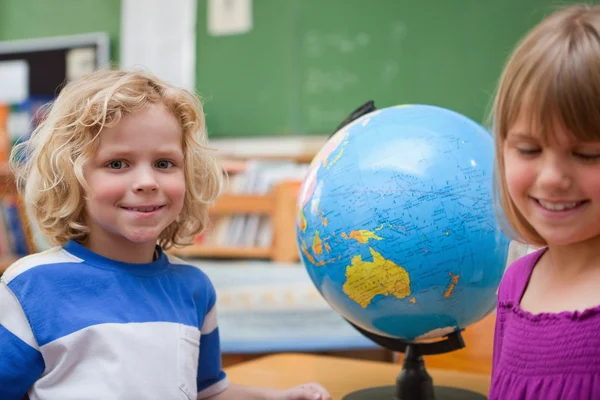 Young pupils posing in front of a globe — Stock Photo, Image