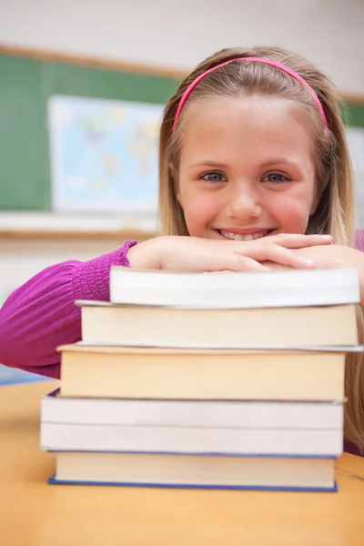 Portret van een glimlachende schoolmeisje poseren met een stapel boeken — Stockfoto