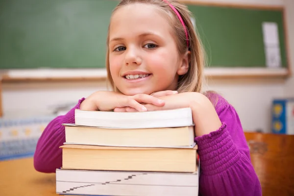 Glückliches Schulmädchen posiert mit einem Stapel Bücher — Stockfoto
