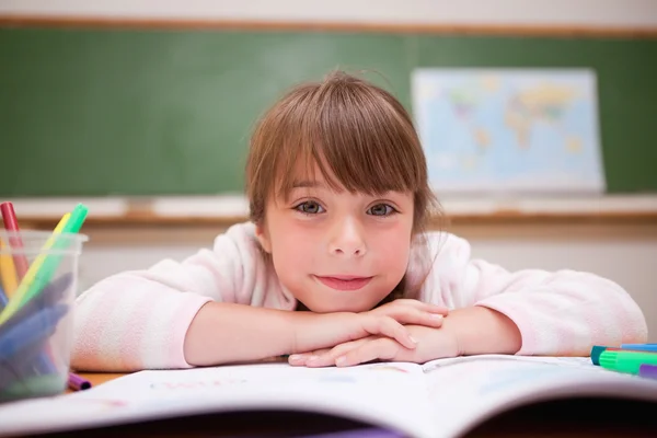 Smiling schoolgirl leaning on a desk — Stock Photo, Image