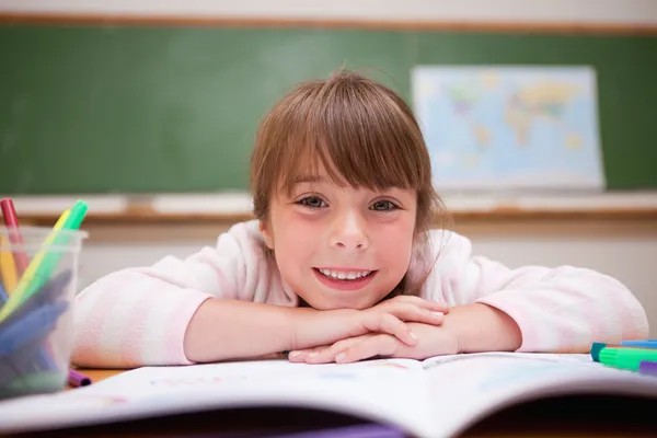 Happy schoolgirl leaning on a desk — Stock Photo, Image