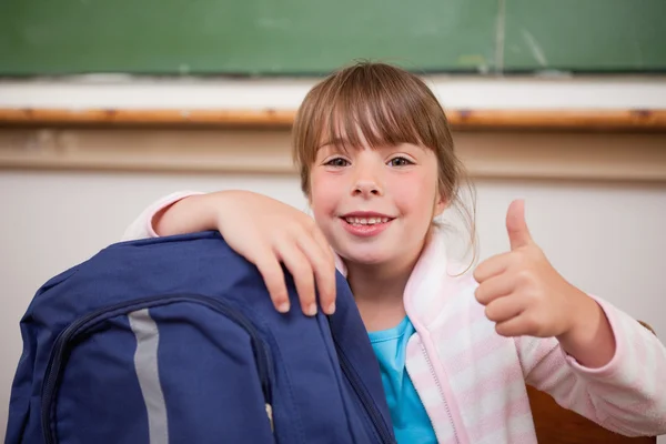 Усміхнена школярка позує з сумкою і великим пальцем вгору — стокове фото