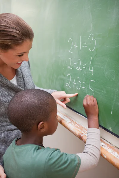 Portrait of a cute teacher and a pupil making an addition — Stock Photo, Image
