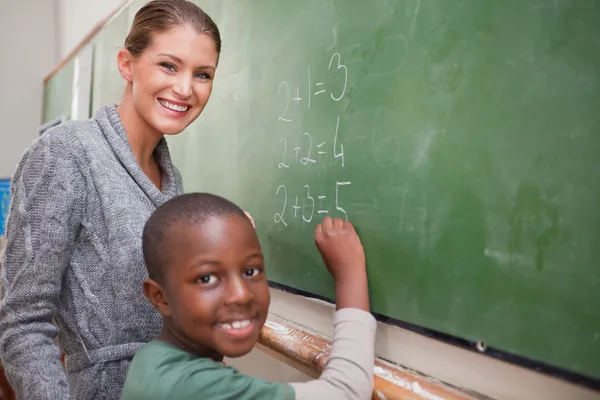 Smiling teacher and a pupil making an addition — Stock Photo, Image