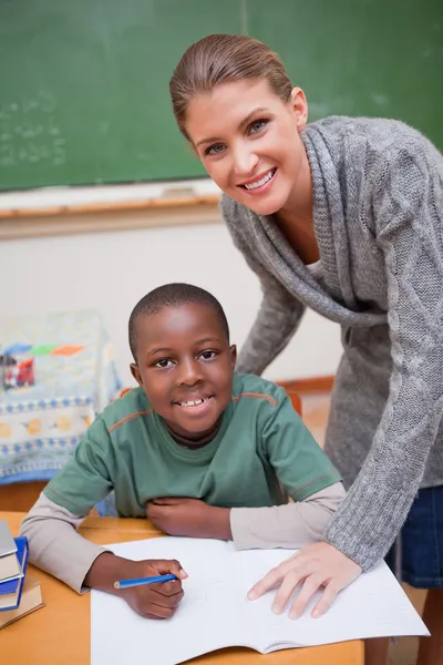 Portret van een leraar iets uit te leggen aan een glimlachende schoolbo — Stockfoto