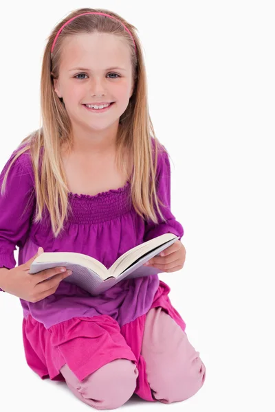 Porträtt av en leende flicka som läser en bok — Stockfoto