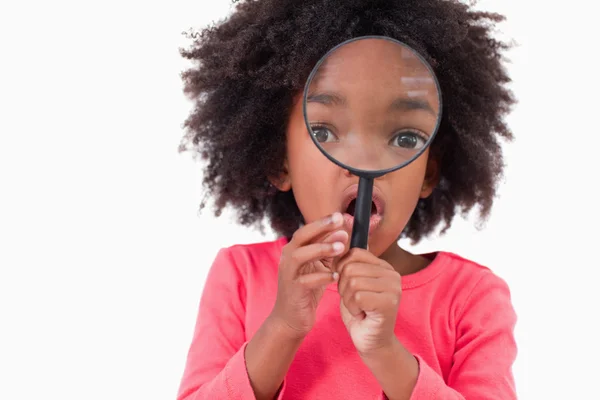 Girl looking through a magnifying glass — Stock Photo, Image