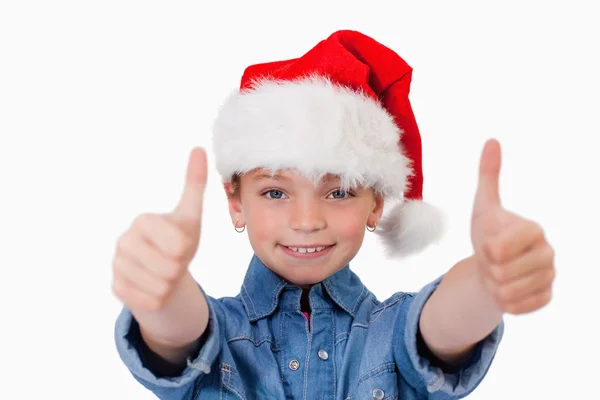 Flicka med en jul-hatt och tummen upp — Stockfoto
