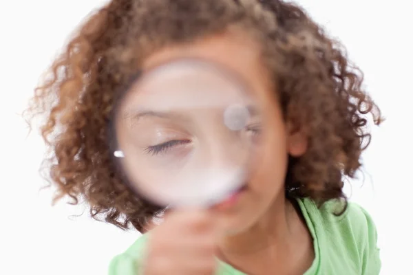 Niedliches Mädchen, das durch ein Vergrößerungsglas schaut — Stockfoto