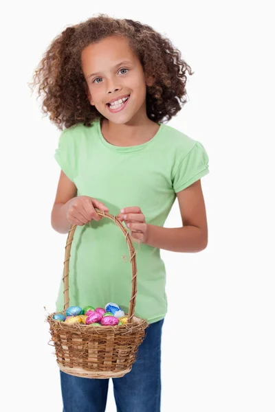 Portrait of a young girl holding a basket full of Easter eggs — Stock Photo, Image