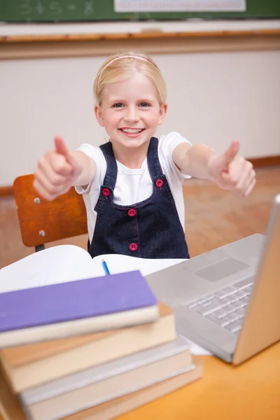Portret van een meisje met behulp van een laptop met de duimen omhoog — Stockfoto