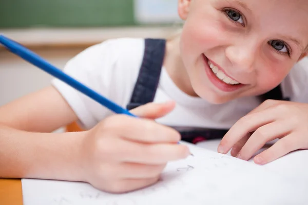 Gros plan d'une écolière souriante écrivant quelque chose — Photo