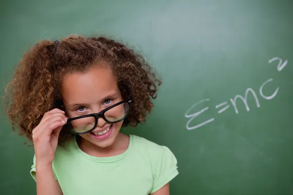 Розумна школярка дивиться над окулярами — стокове фото