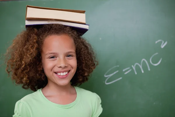 Счастливая школьница с книгой на голове — стоковое фото