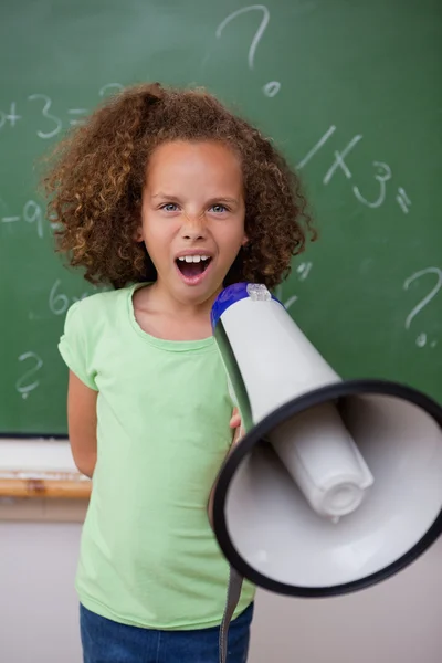 Portrait of a young schoolgirl screaming through a megaphone — Stock Photo, Image