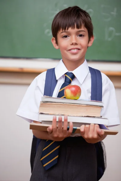 Ritratto di uno scolaro che tiene libri e una mela — Foto Stock