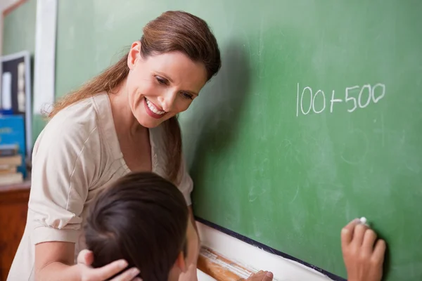 Lachende onderwijzer helpen een schooljongen doen een toevoeging — Stockfoto