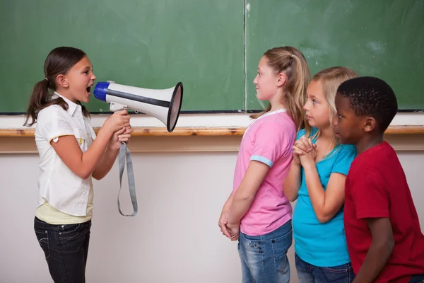 Angry schoolgirl screaming through a megaphone to her classmates — Stock Photo, Image