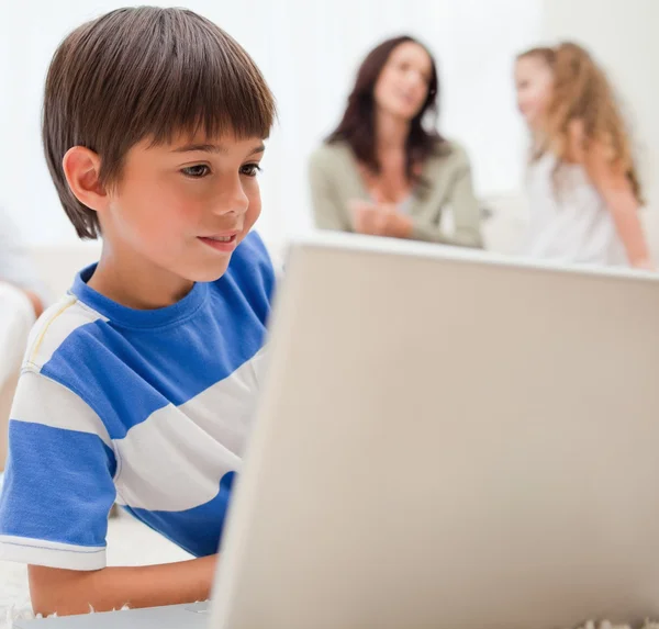 Onun arkasında onun ailesi ile bilgisayar oyunu oynamak çocuk — Stok fotoğraf