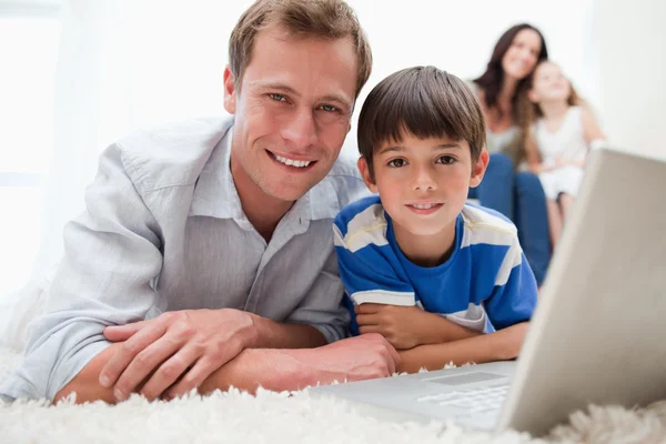 Jongen met zijn vader met behulp van laptop op het tapijt — Stockfoto