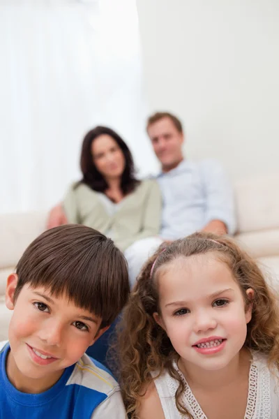 Kinder sitzen im Wohnzimmer, die Eltern im Hintergrund — Stockfoto