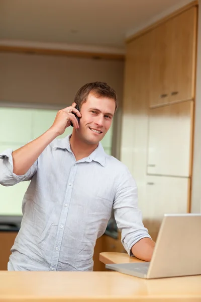 Male with laptop and cellphone in the kitchen — Stock Photo, Image