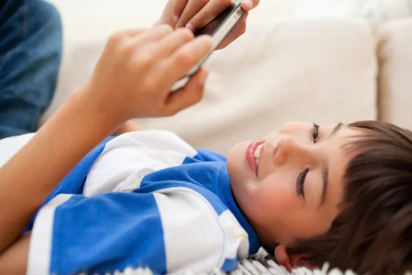 Junge liegt auf dem Teppich und spielt mit seinem Handy — Stockfoto