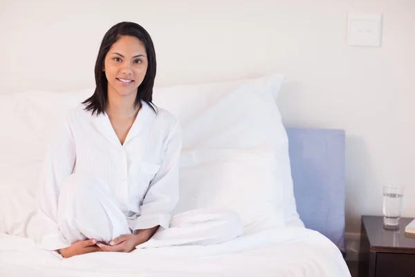 Женщина в пижаме сидит на кровати — стоковое фото