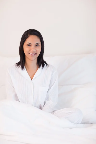 パジャマを着て、ベッドの上に座っている女性の笑みを浮かべてください。 — ストック写真